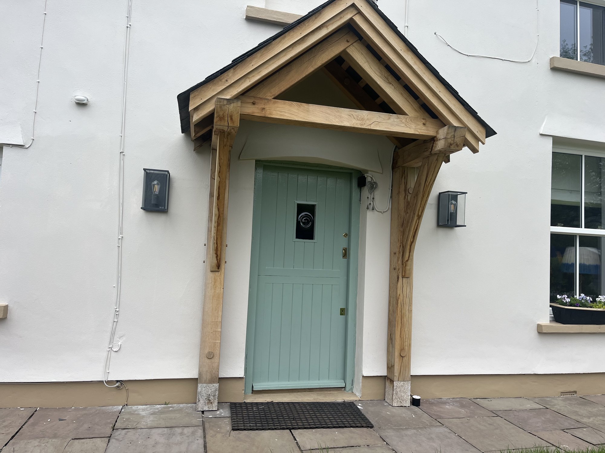 Oak gable porch over a pale green front door on a white rendered house near Usk