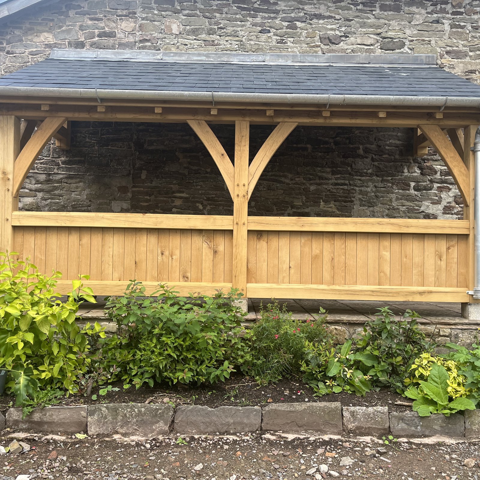 Oak lean-to with curved braces and a boarded balustrade