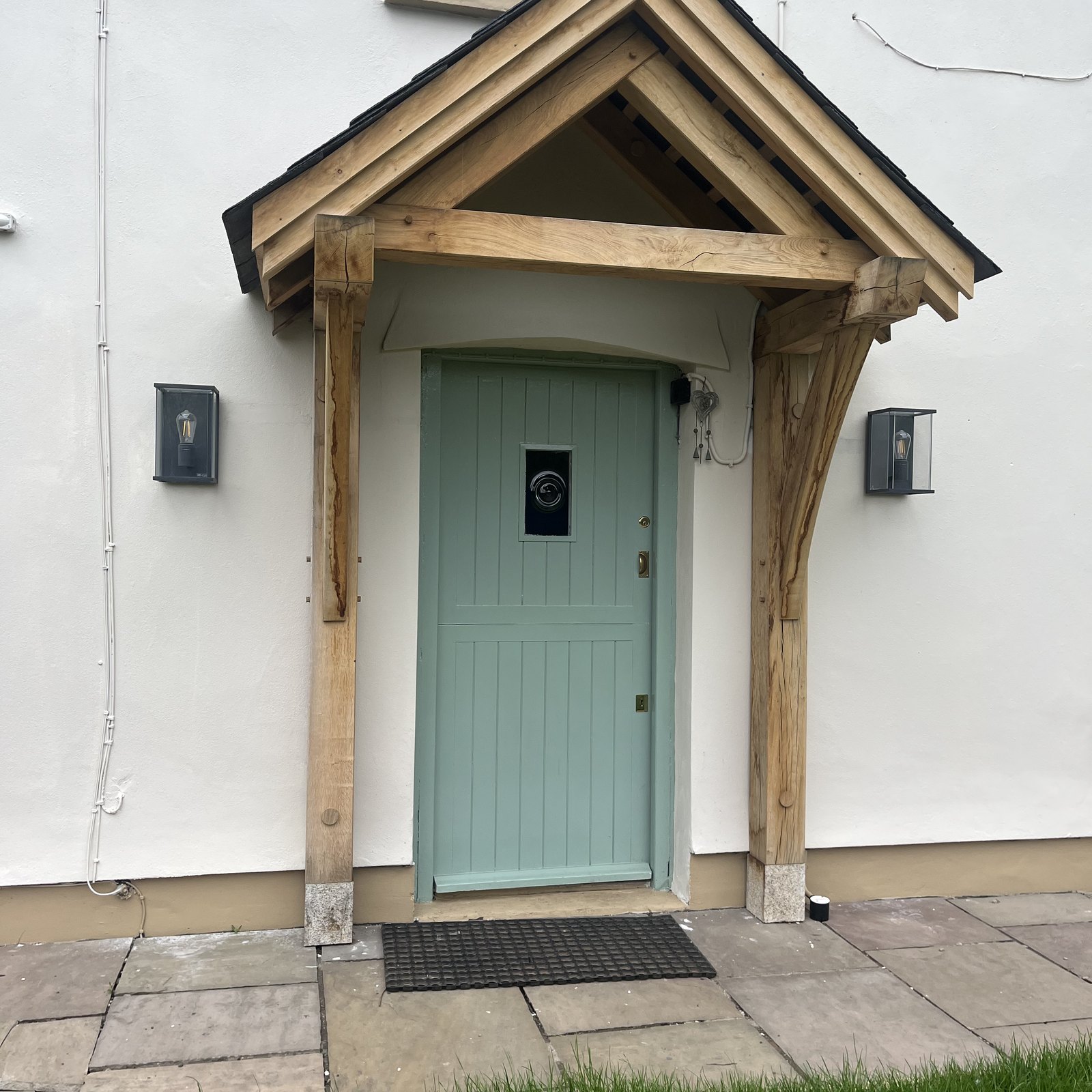 Oak gable porch over a pale green front door