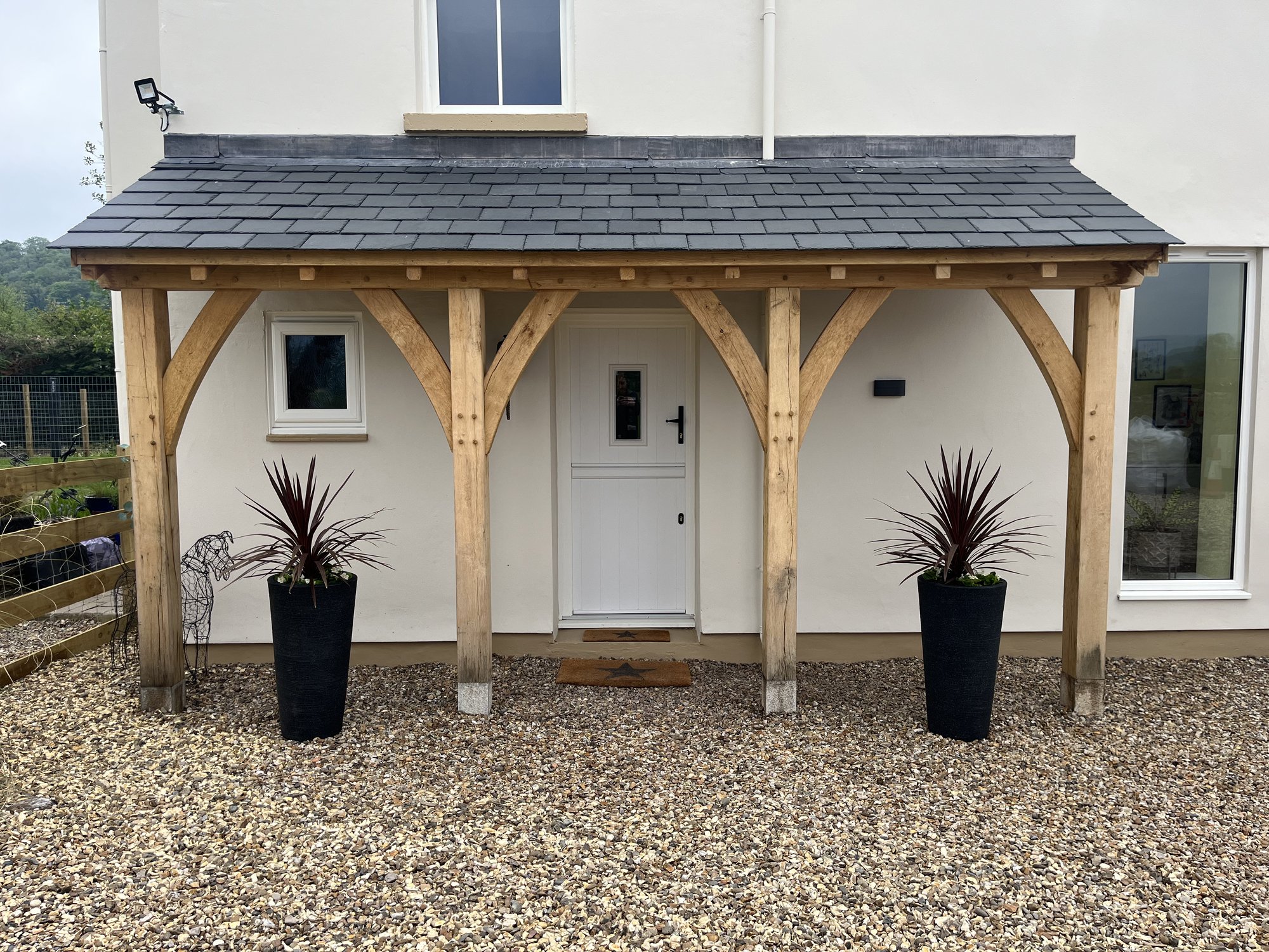 A long oak lean-to porch along a white rendered house near Usk
