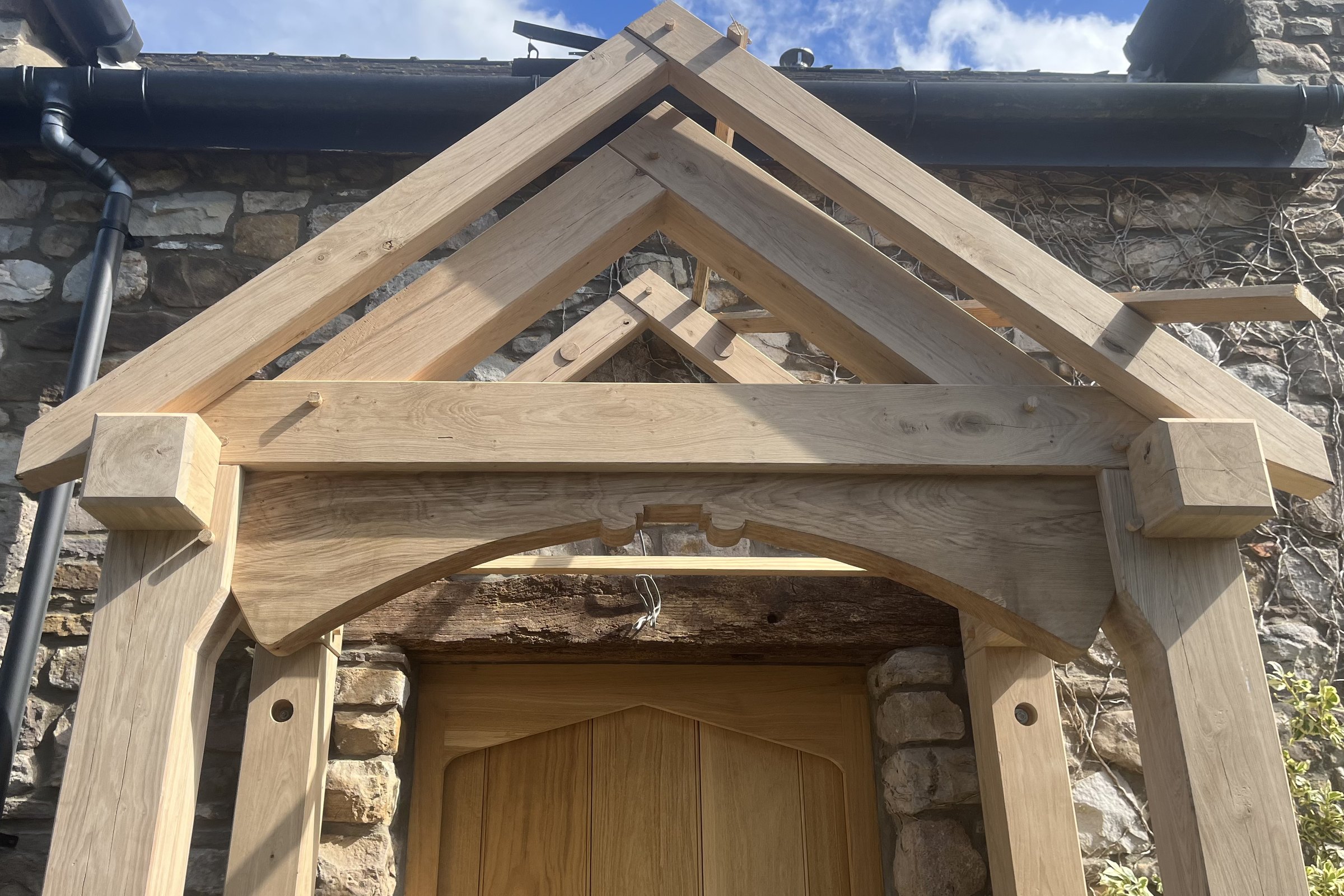Oak gable porch with curved braces on a stone cottage at Goytre