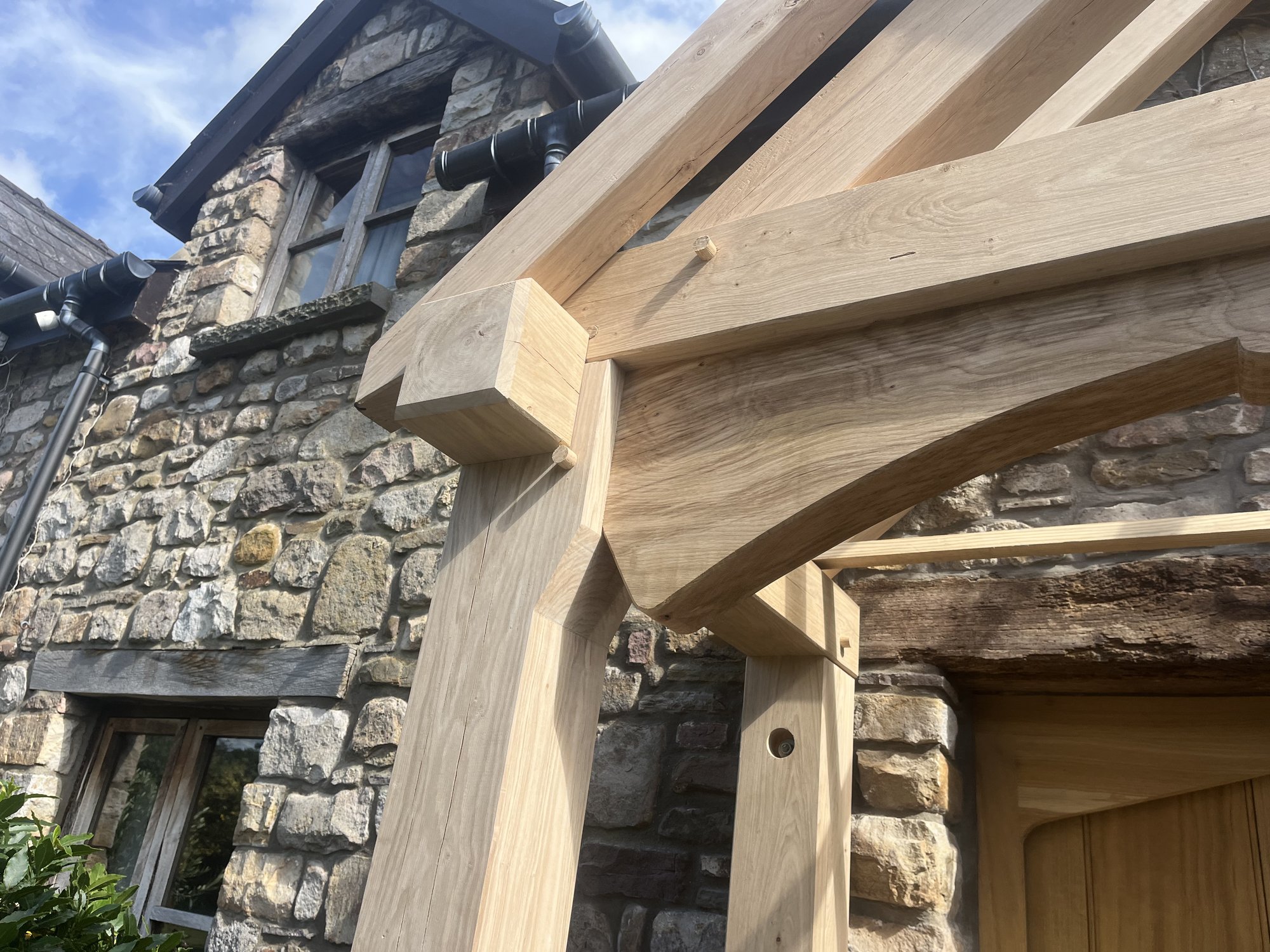 Close view of a curved oak tie beam and braces on a porch at Goytre