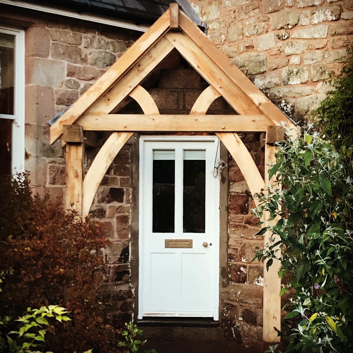 Oak gable porch with curved braces over a white front door
