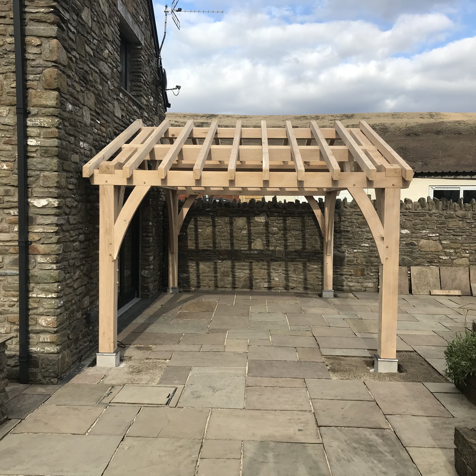 Oak frame garden pavilion with curved braces on a paved terrace