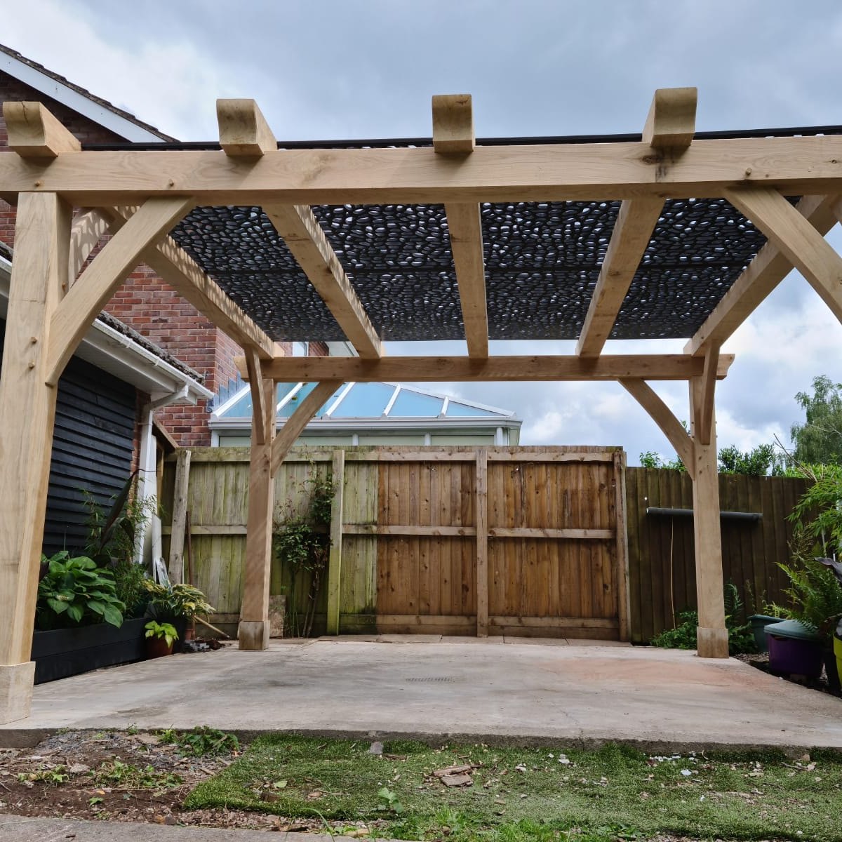 Oak pergola with a patterned shade screen over a patio