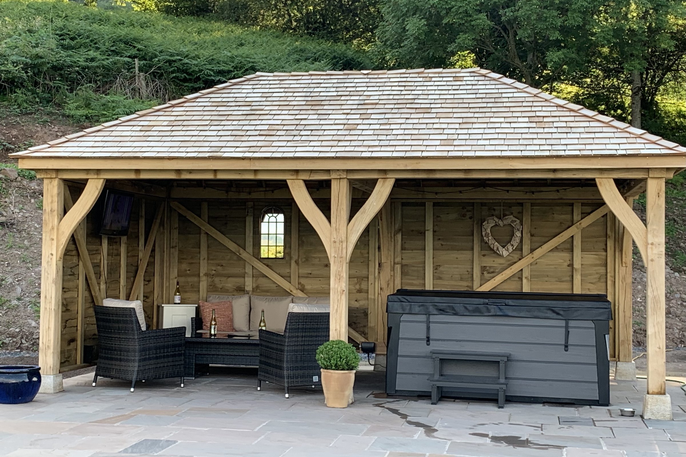Oak frame gazebo with a cedar shingle hipped roof over a hot tub at Gilwern