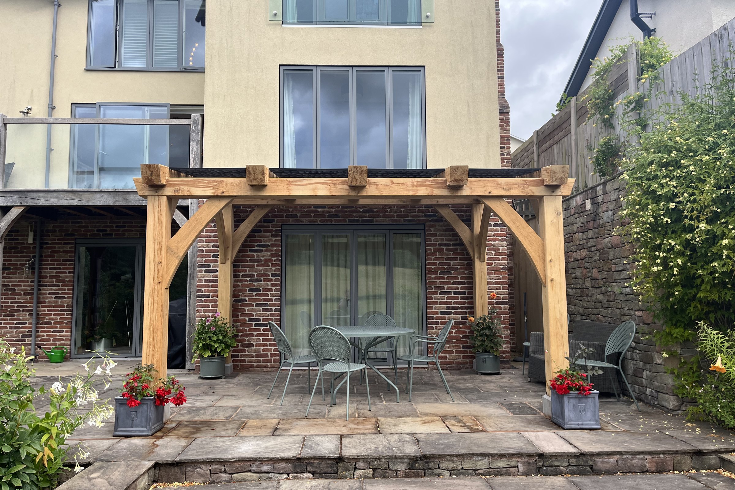 Oak pergola over a stone terrace behind a house at Grosmont