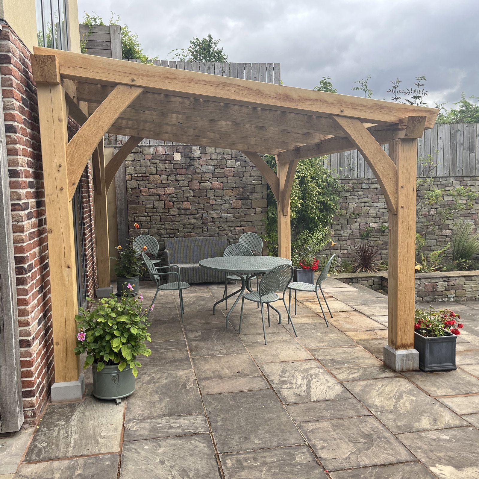 Oak pergola with curved braces over a paved terrace