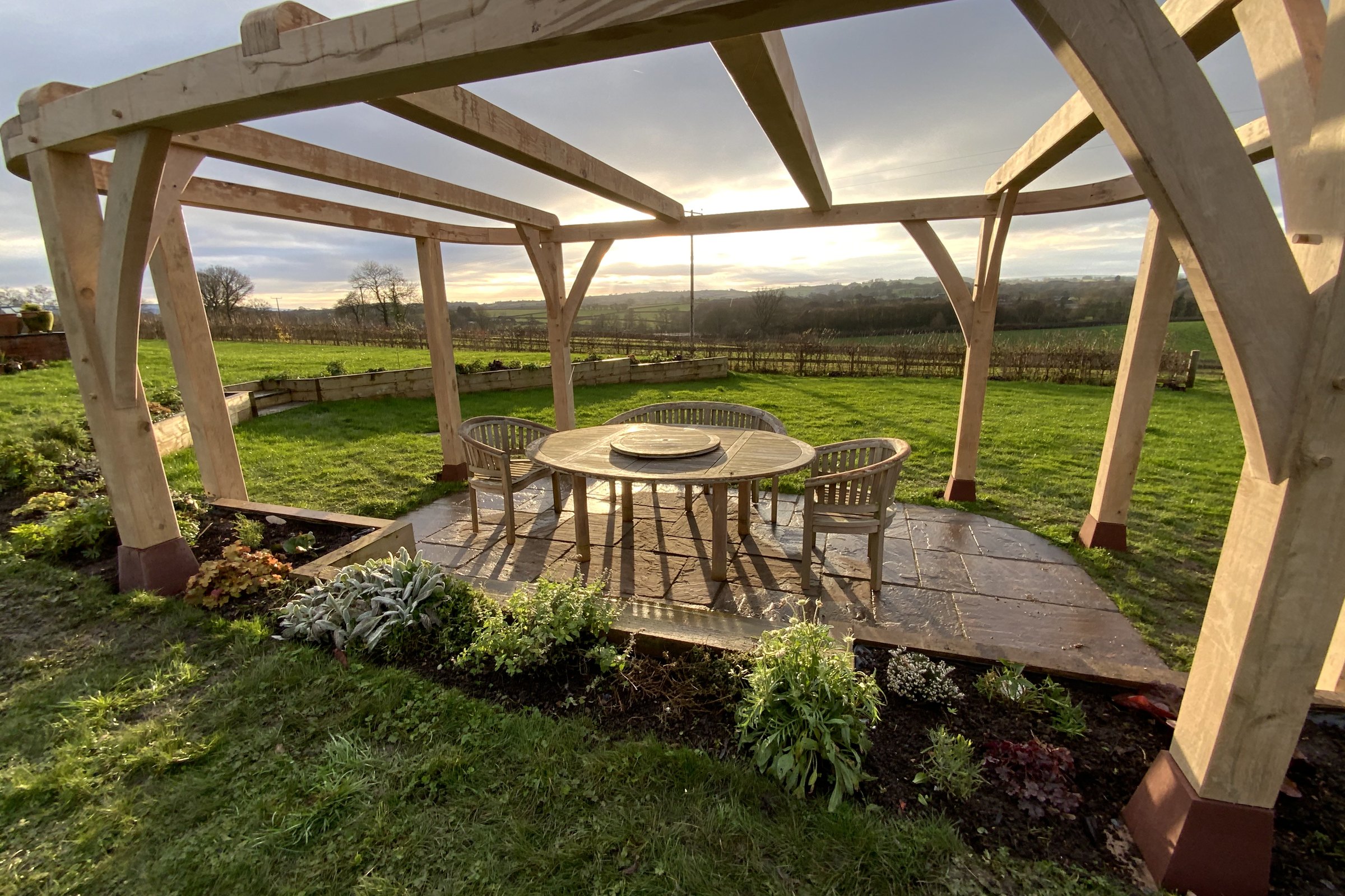 Oak pergola with curved braces over a garden dining area at Raglan
