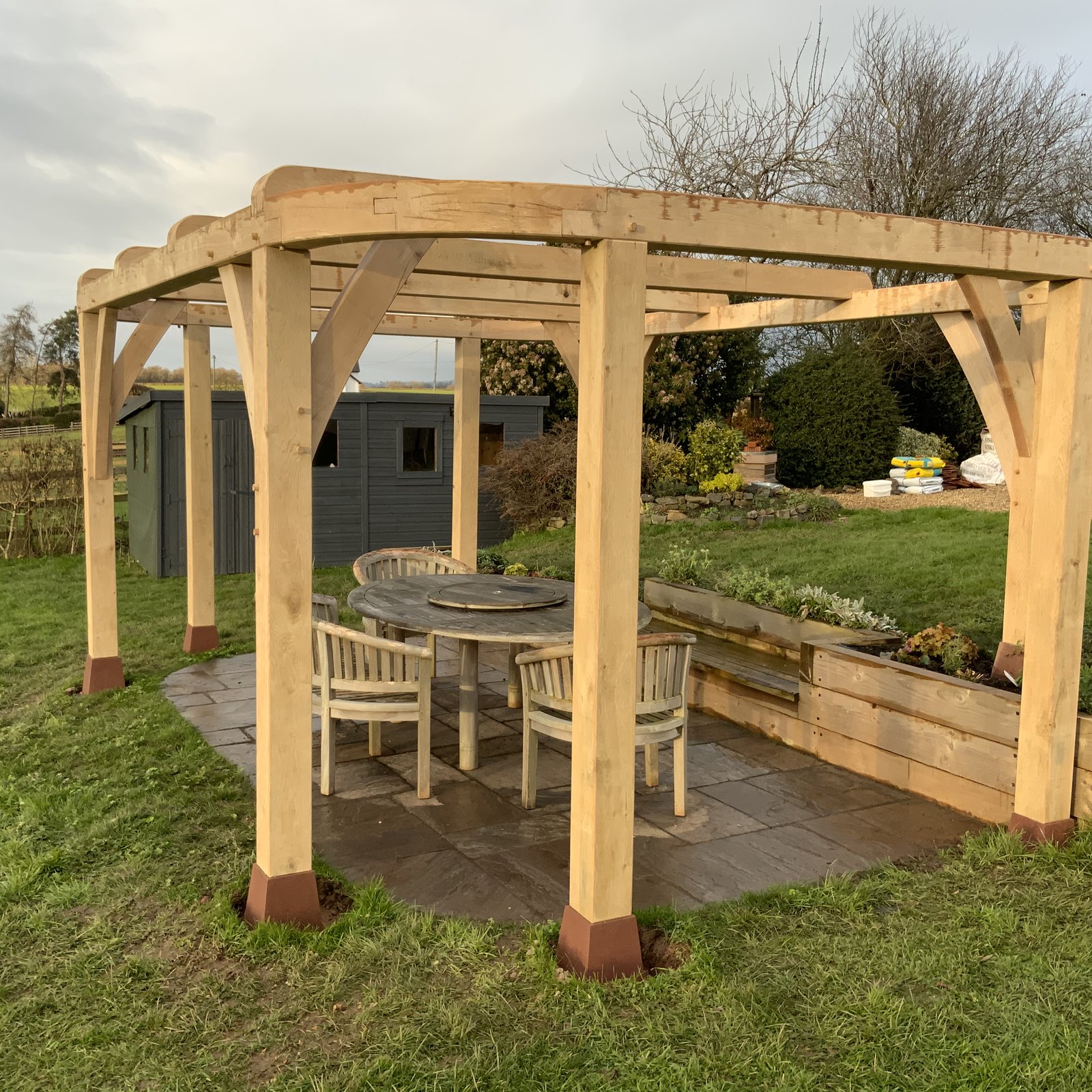 Oak pergola over a garden table and chairs