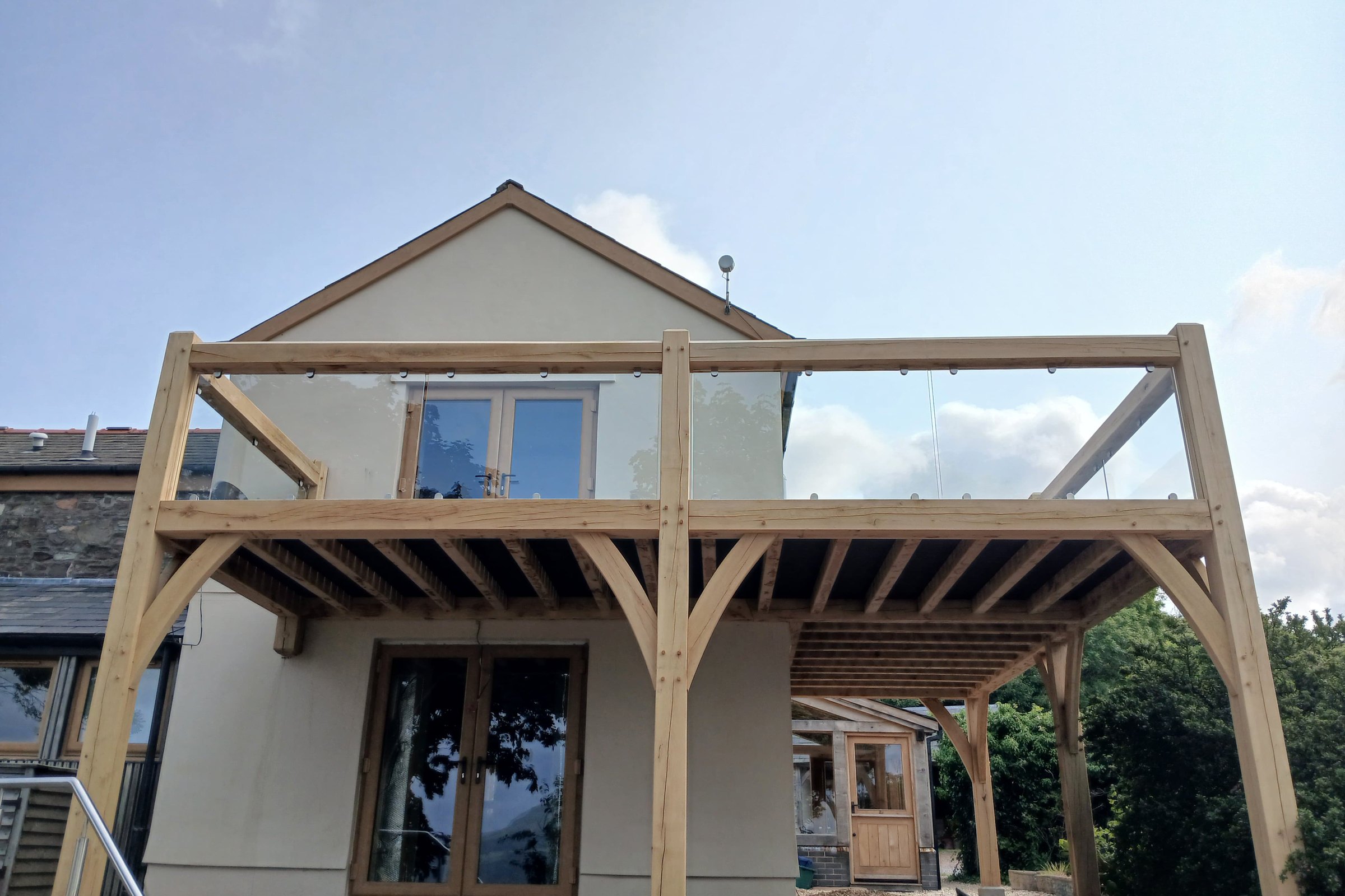 Oak frame balcony with glass balustrade on a rendered house