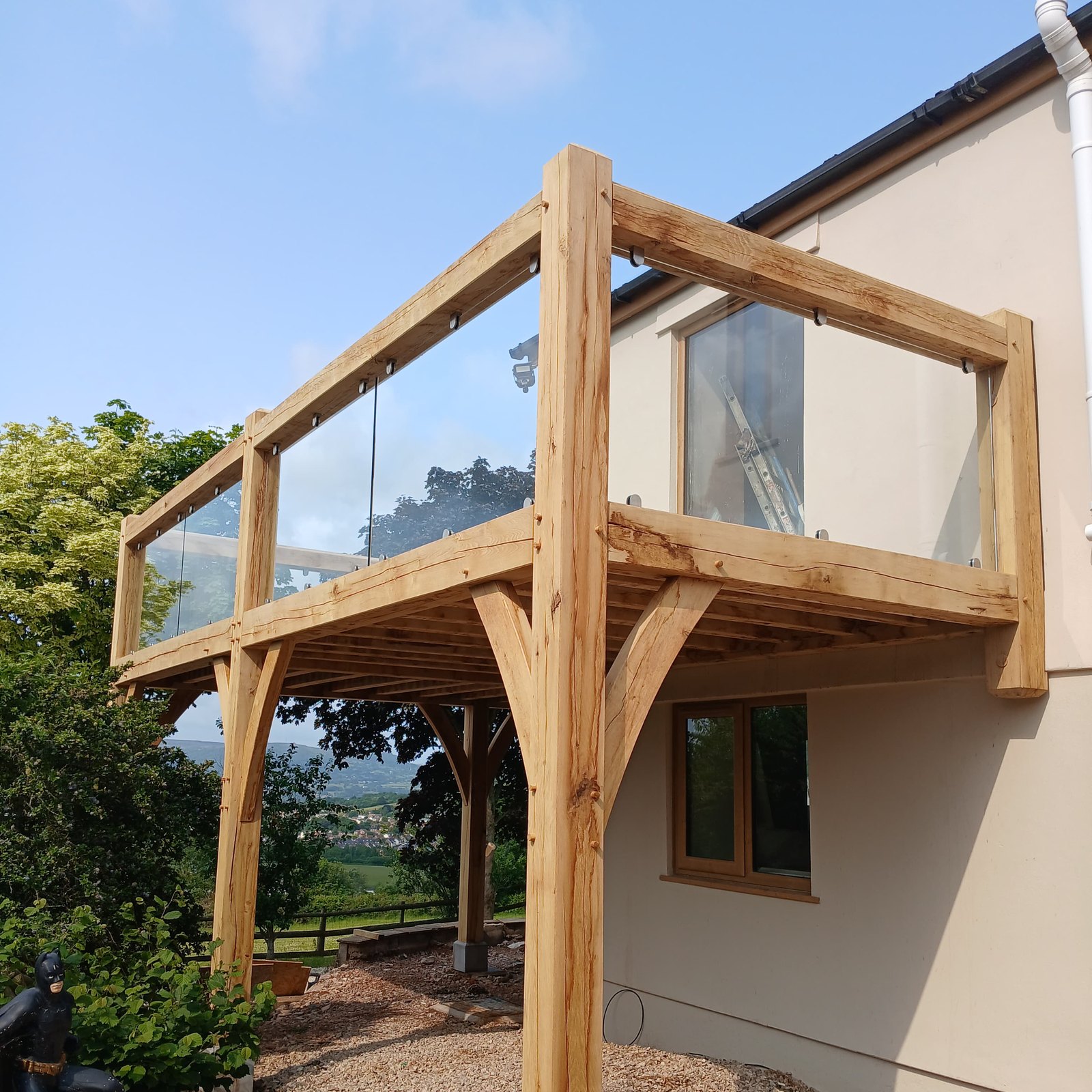 Oak frame balcony with a glass balustrade and curved braces