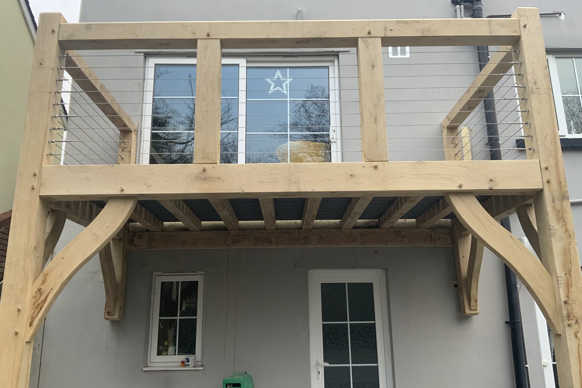 Oak frame balcony with a steel wire balustrade on a rendered house