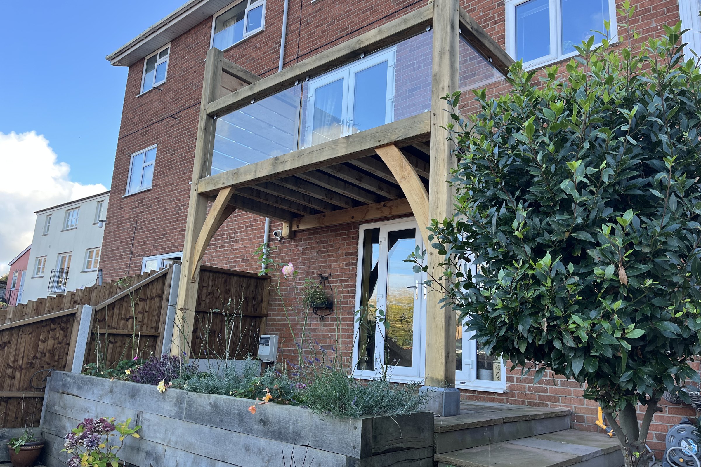 Oak frame balcony with a glass balustrade on a brick house at Llanfoist
