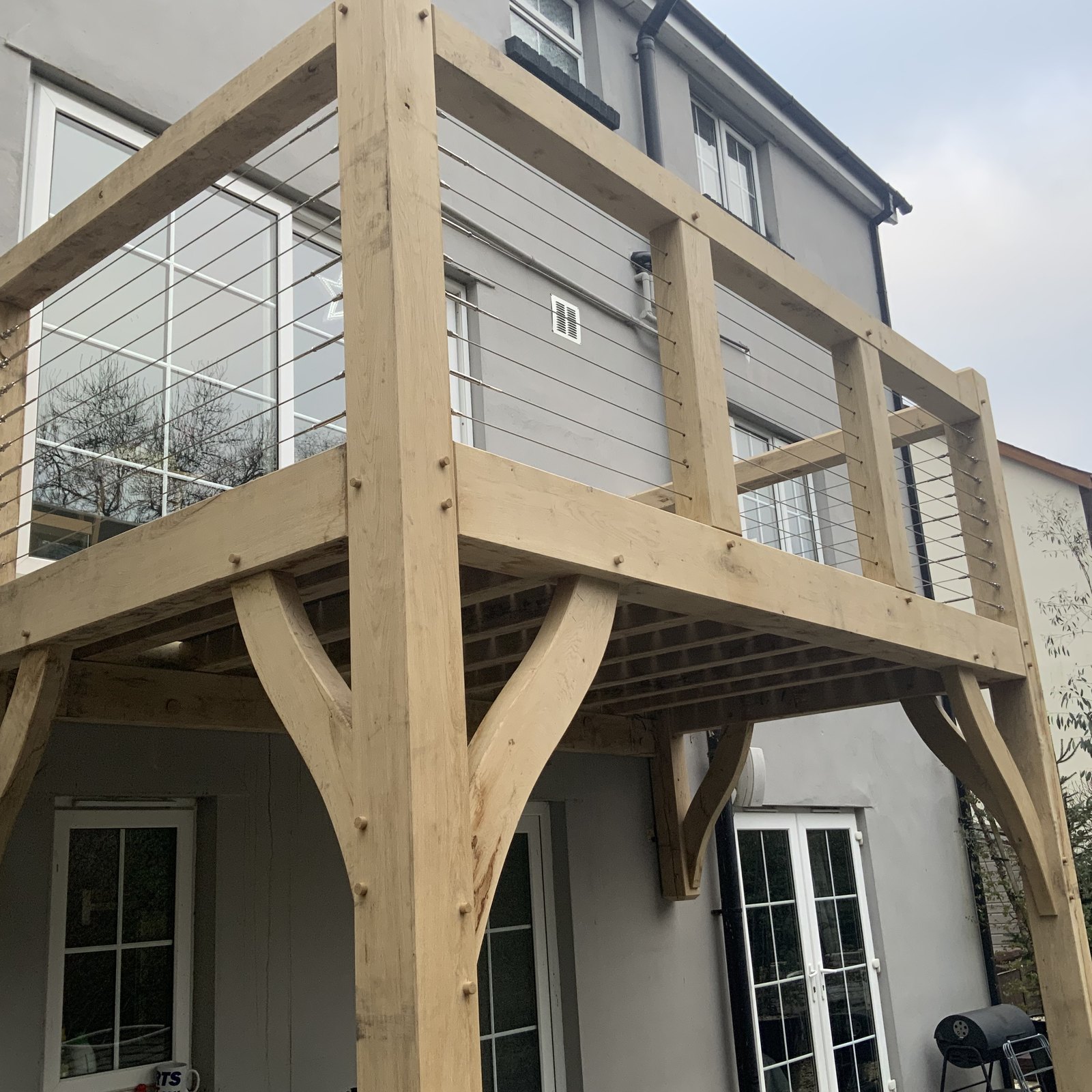 Oak balcony with curved braces and a wire balustrade