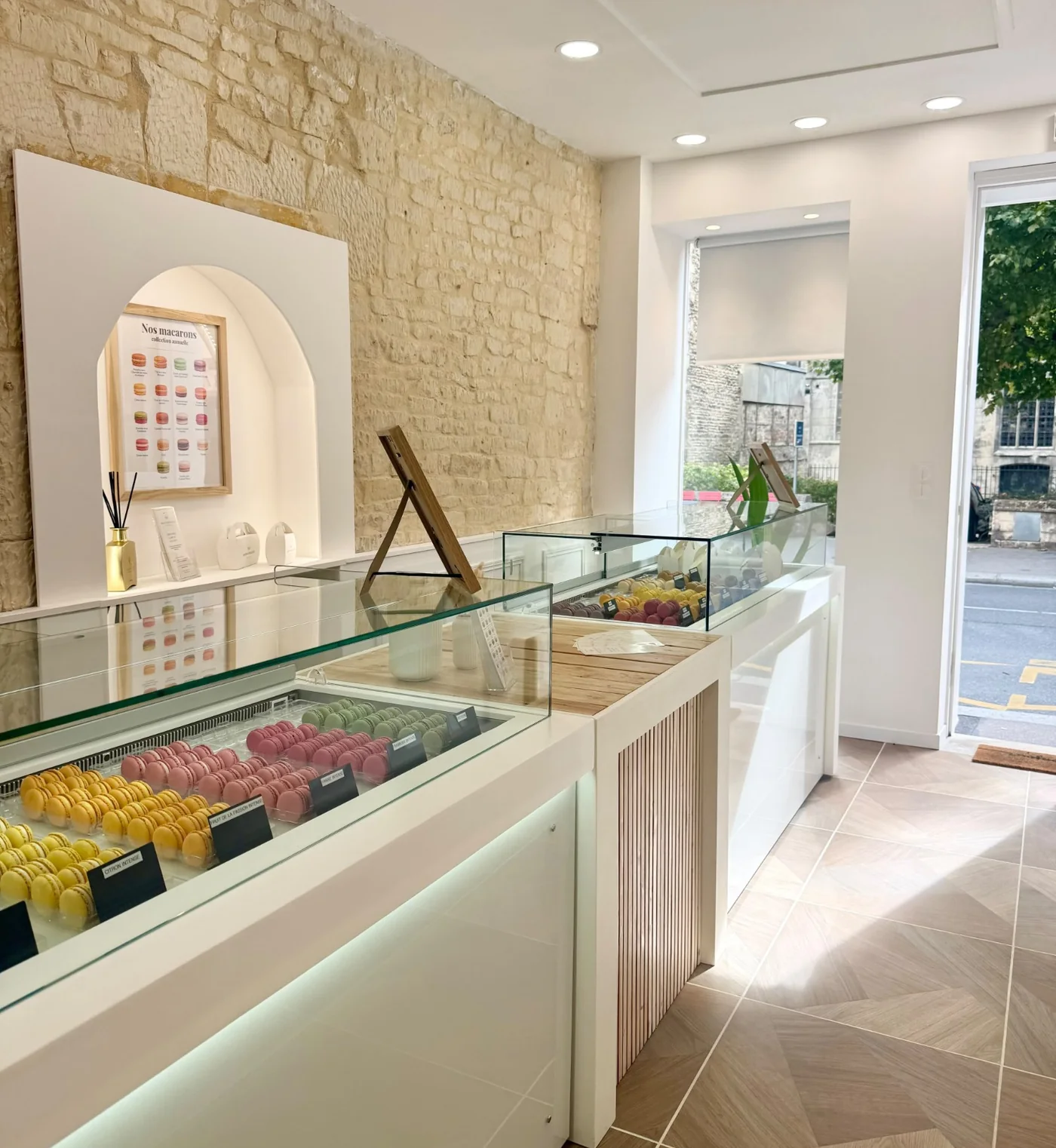 Vitrines de macarons de la boutique Maison Derollier à Caen, devant le mur en pierre apparente.