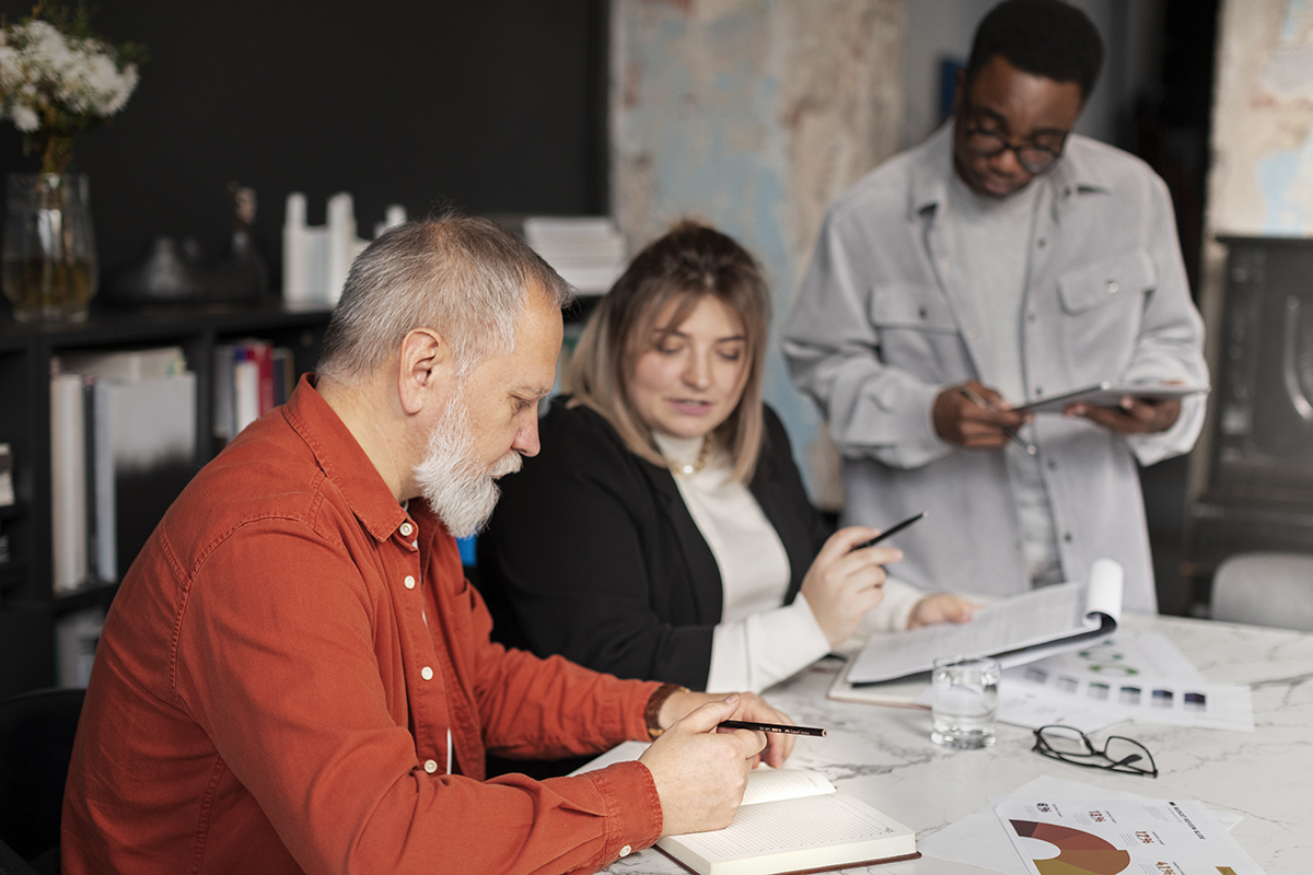 Three colleagues reviewing documents and taking notes together at a conference table