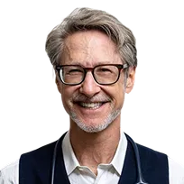 Smiling middle-aged man with gray hair, glasses, and a beard wearing a white shirt and dark vest.