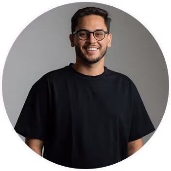 Smiling man with glasses wearing a black t-shirt against a plain gray background.
