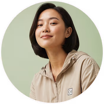 Smiling young woman with short dark hair wearing a beige zip-up jacket against a light green background.