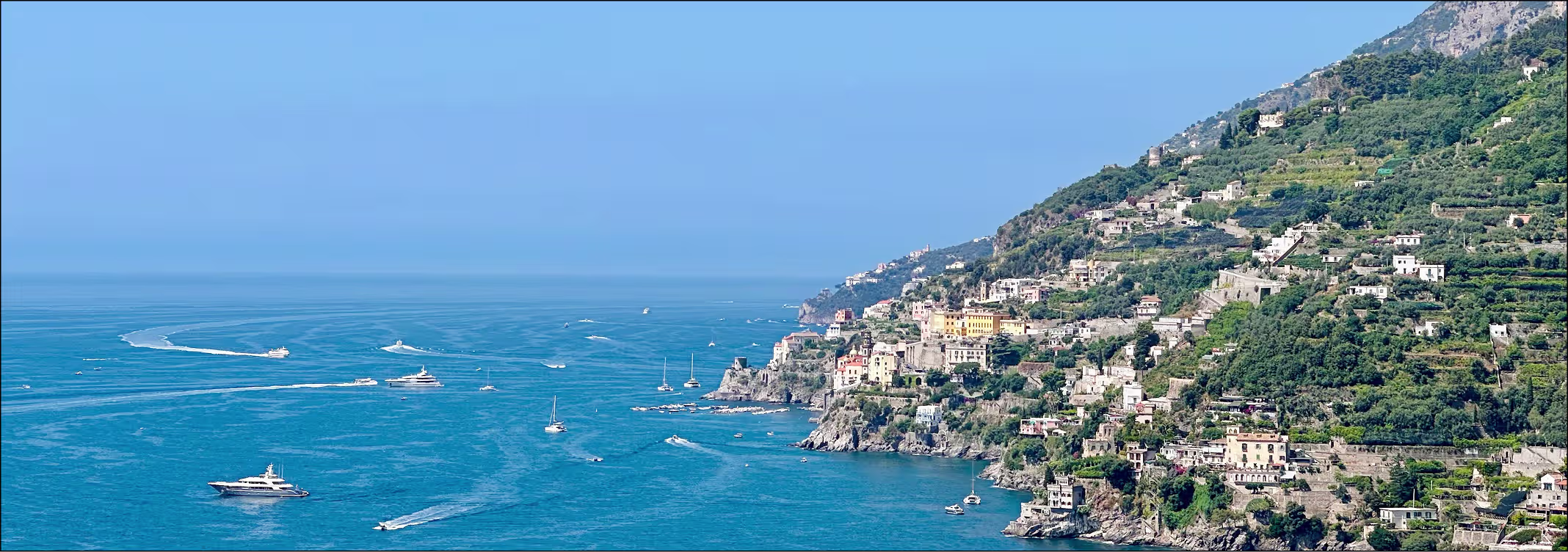Luxury yacht sailing along the Amalfi Coast cliffs