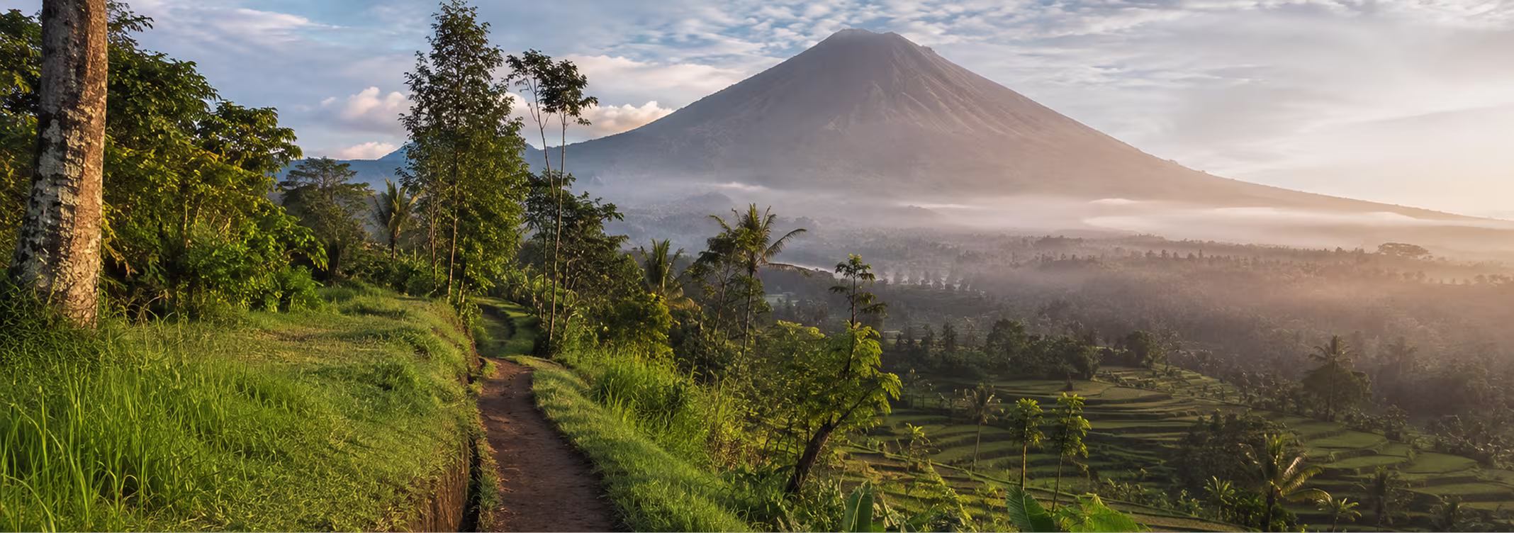 Hiker on jungle trail overlooking Bali volcano