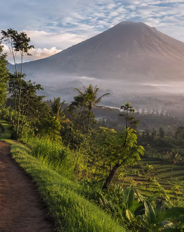 Hiker on jungle trail overlooking Bali volcano