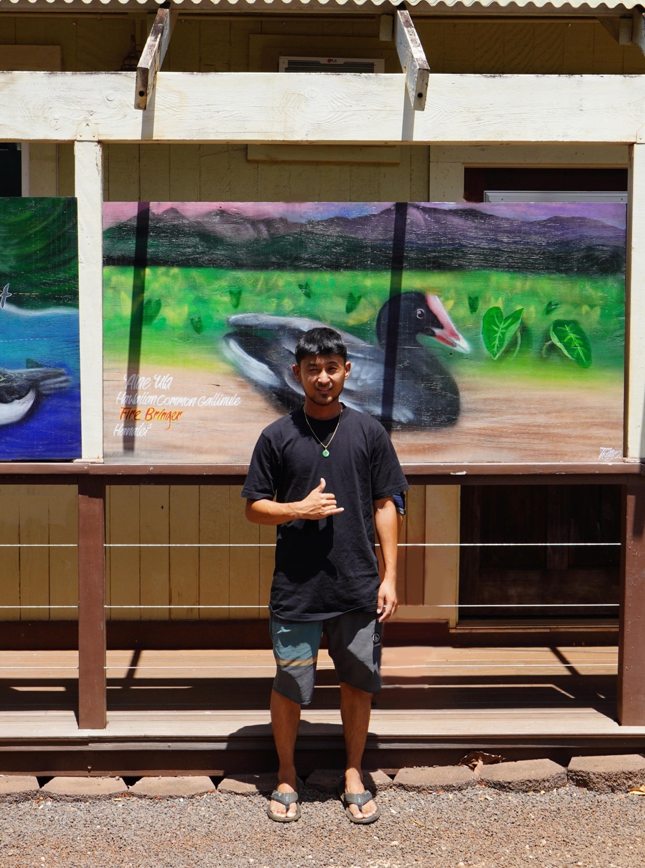 Trysen Kaneshige throwing a shaka in front of the installed ʻalae ʻula and ʻuaʻu panels