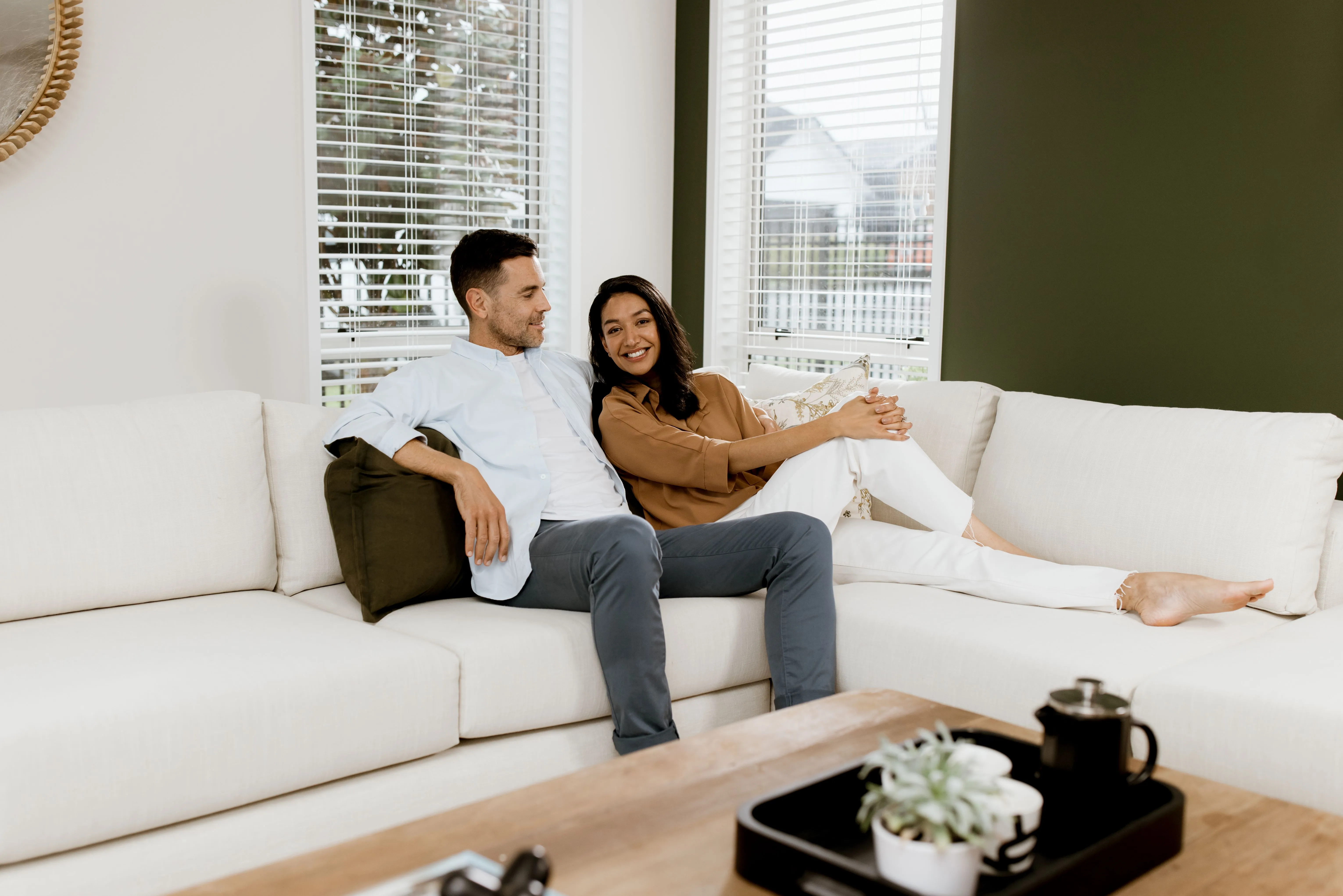 Couple sitting on a couch feeling happy they're house is now running on solar power and saving the planet
