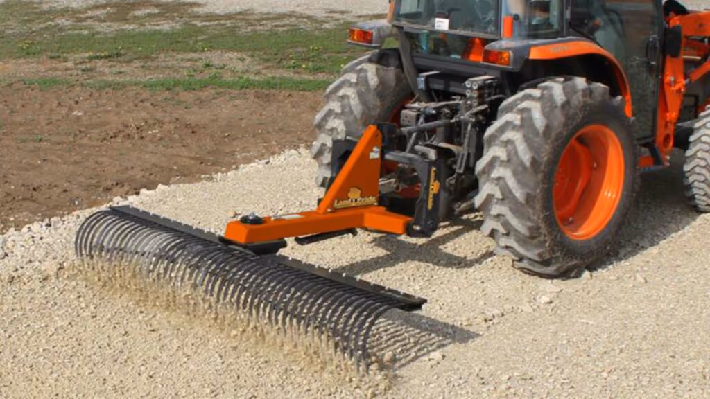 Orange rake attachment with rows of steel tines.