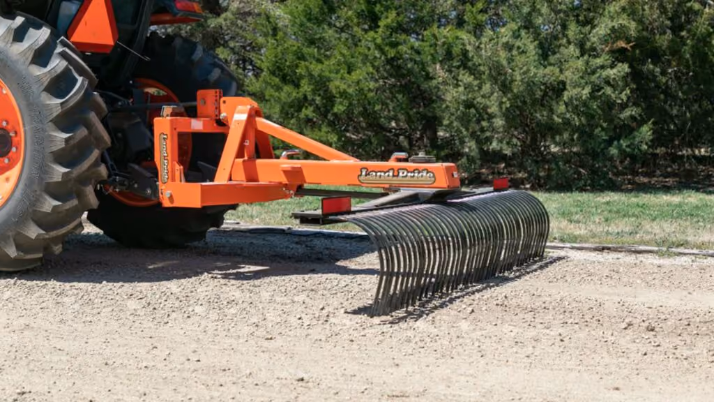 Orange rake attachment with rows of steel tines.