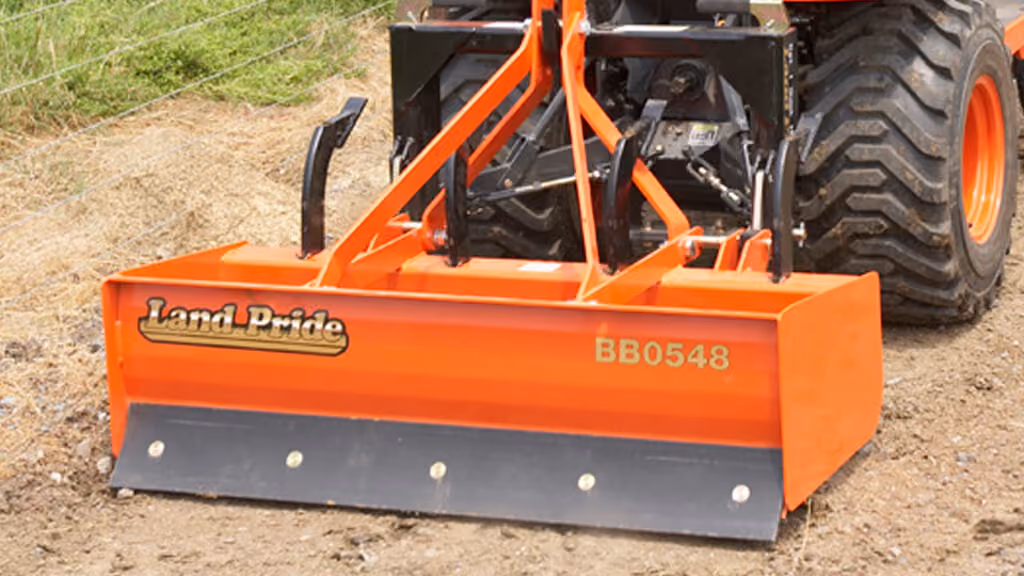 Orange grading attachment with wide steel blade.