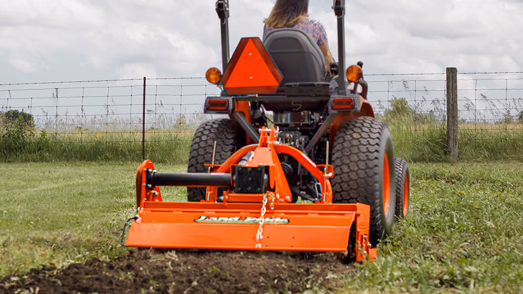 Orange rotary tiller attachment for breaking up soil.