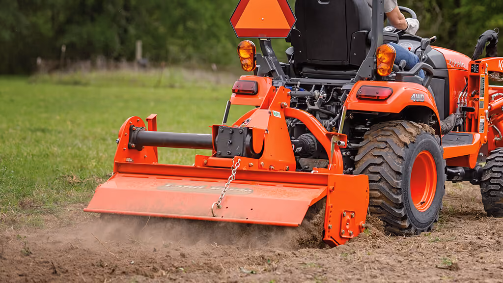 Orange rotary tiller attachment for breaking up soil.