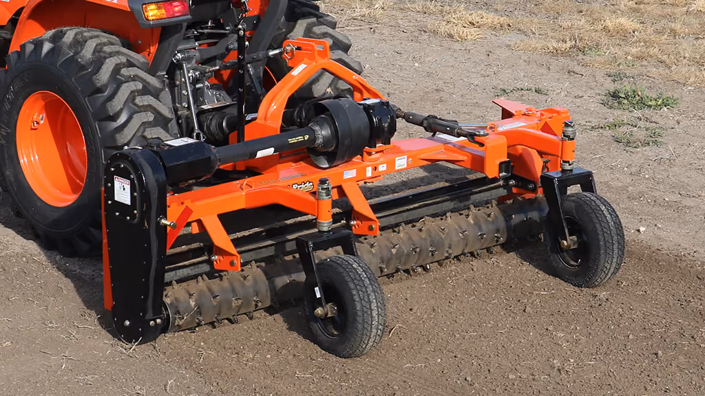 Orange rake attachment with rows of steel tines.