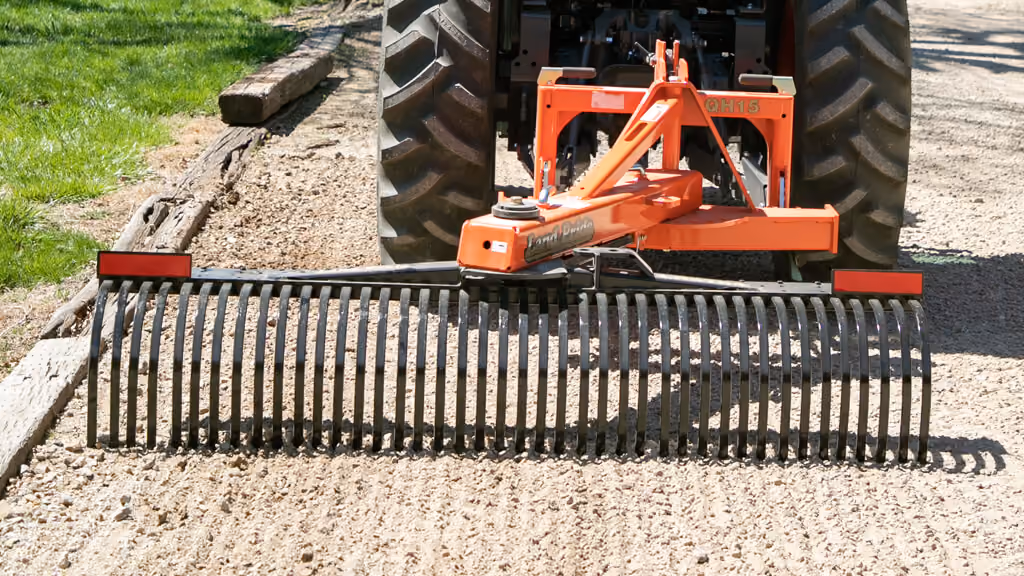 Orange rake attachment with rows of steel tines.