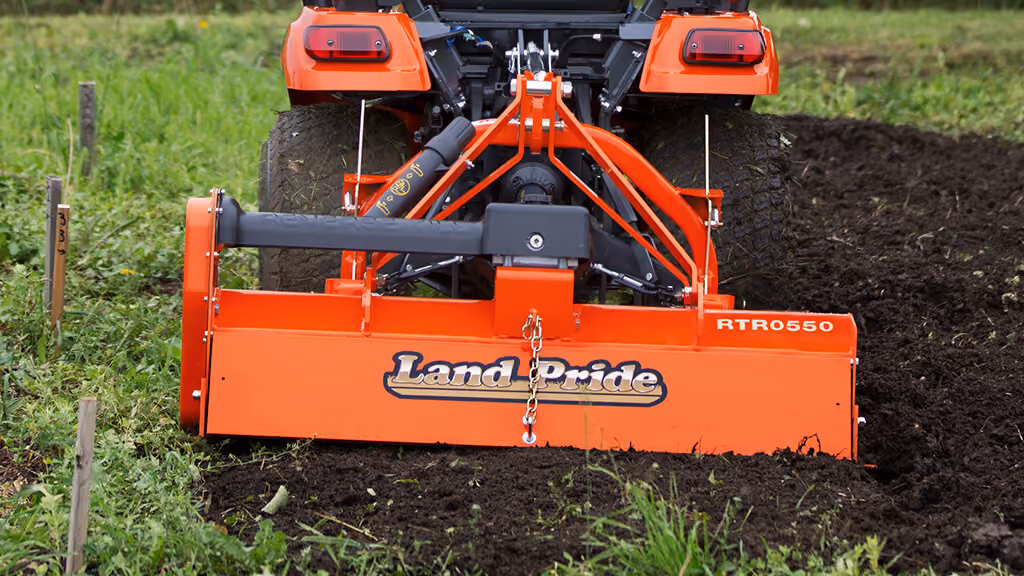 Orange rotary tiller attachment for breaking up soil.