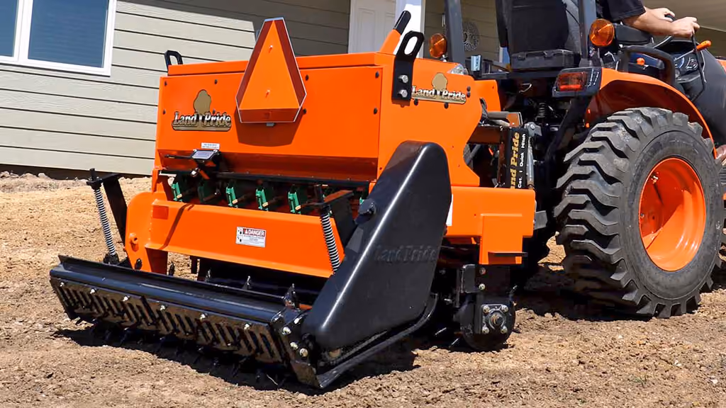 Orange seeder attachment for preparing and planting soil.