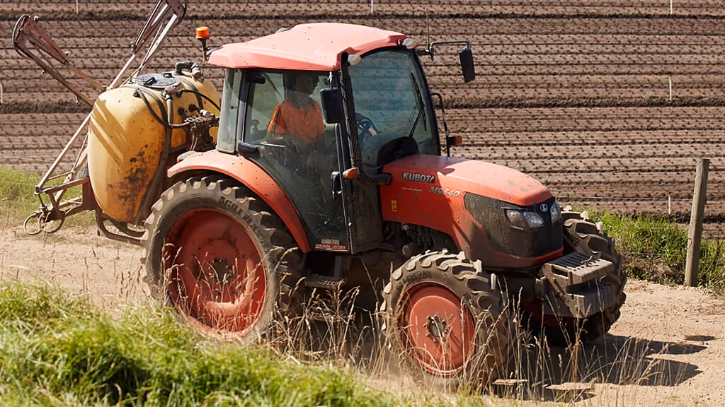 Orange Kubota tractor with roll-over protection.
