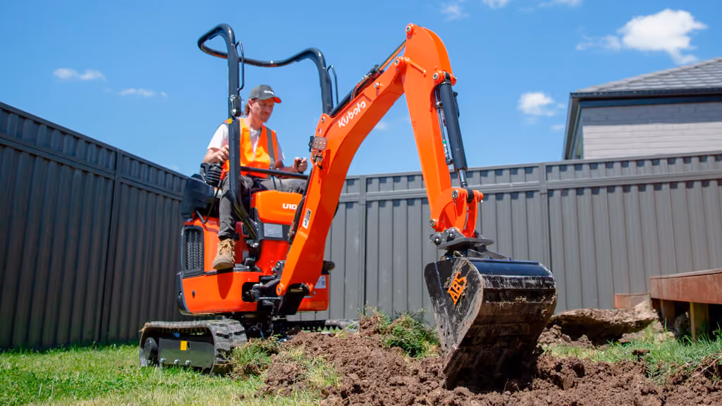 Orange Kubota excavator with tracked undercarriage and digging arm.