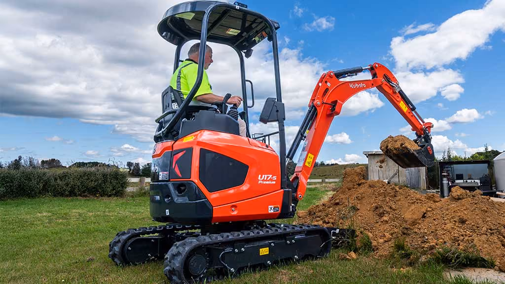 Orange Kubota excavator with tracked undercarriage and digging arm.