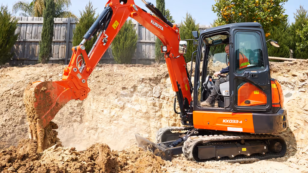 Orange Kubota excavator with tracked undercarriage and digging arm.