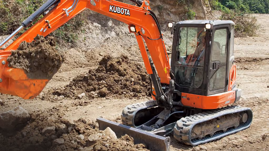 Orange Kubota excavator with tracked undercarriage and digging arm.