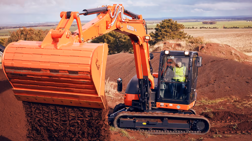 Orange Kubota excavator with tracked undercarriage and digging arm.