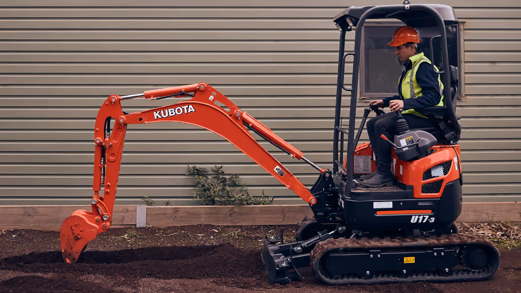 Orange Kubota excavator with tracked undercarriage and digging arm.