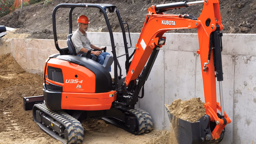 Orange Kubota excavator with tracked undercarriage and digging arm.