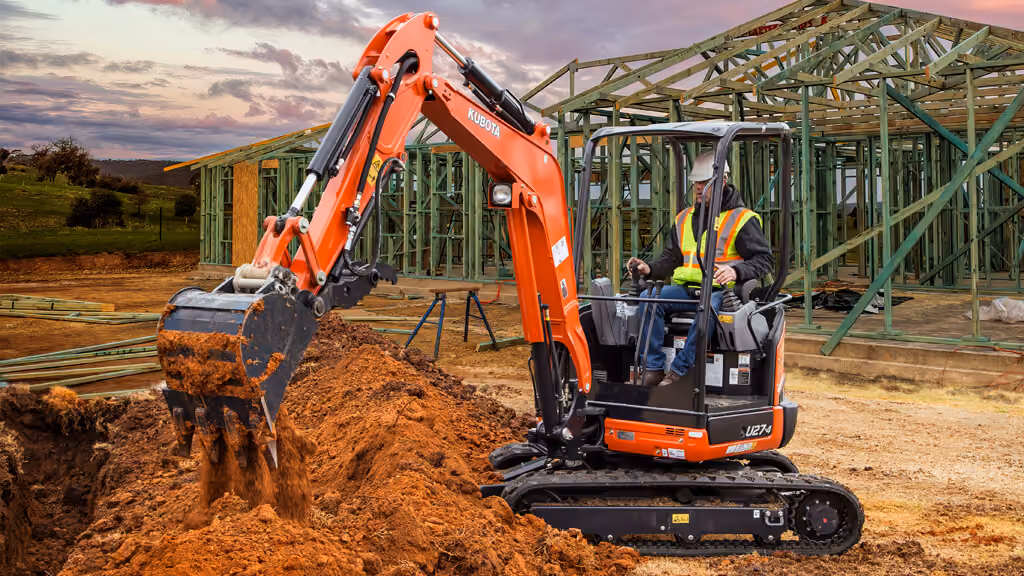 Orange Kubota excavator with tracked undercarriage and digging arm.