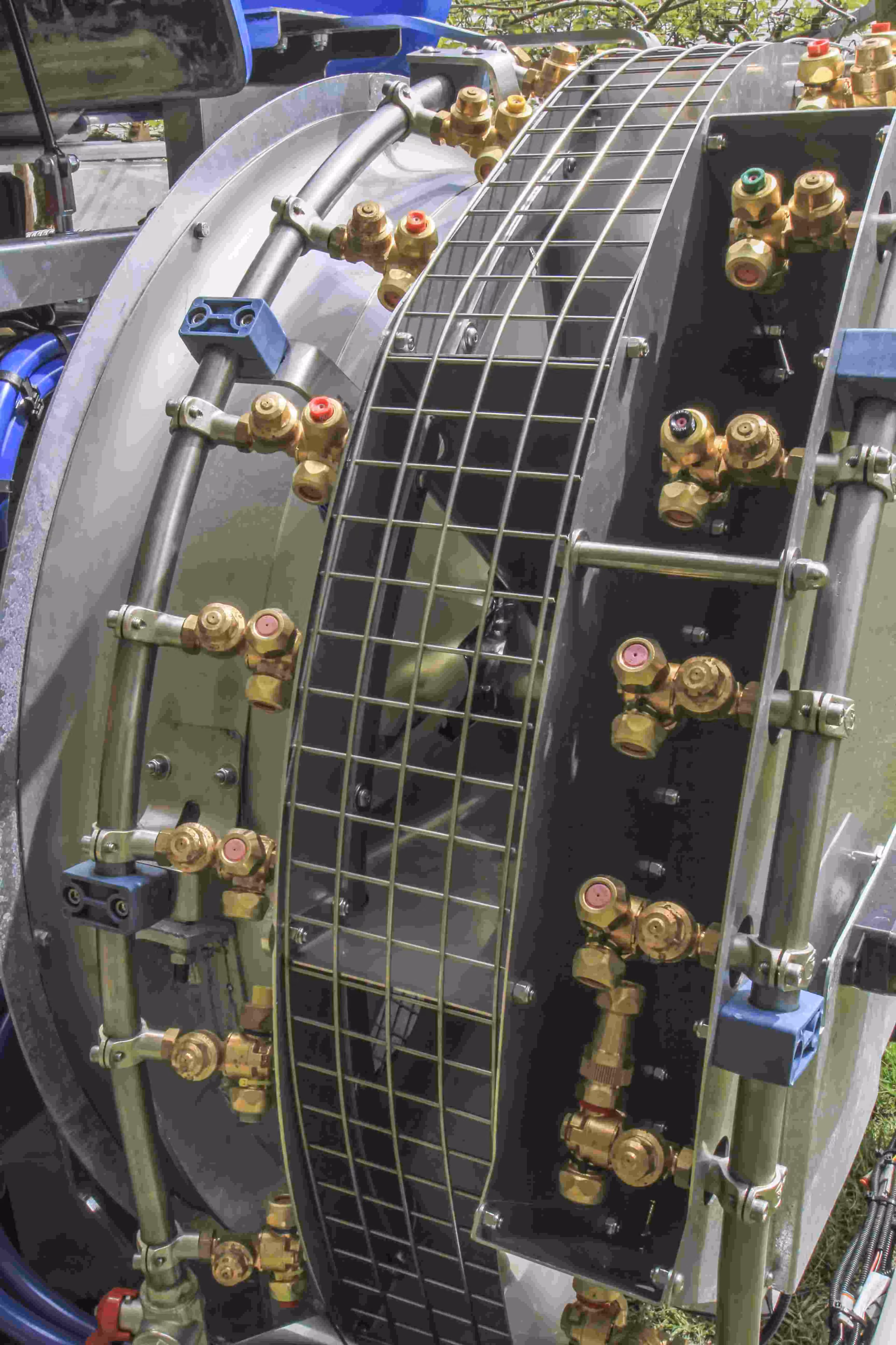 Double spray ring on the sprayer's fan: two rings of brass nozzle bodies with coloured caps around a mesh guard.