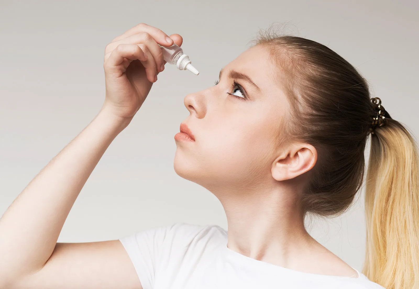 Girl using eye drops as part of dry eye treatment at Neil Gordon Opticians