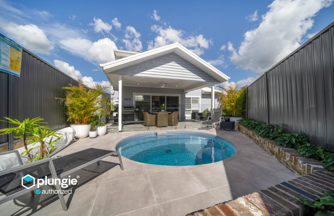 Plungie Arena 11'5" round precast concrete pool aerial view with curved steps and sparkling water — installed by DropIn Oasis Pools, Houston's authorized Plungie installer.
